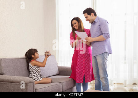 Mutter und Vater holding Dokumente und Tochter sitzen auf einem Sofa, Geld, Stockfoto