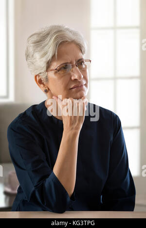 Reife Frau mit Hand am Kinn denken Stockfoto