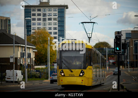 Eine gelbe Manchester Metrolink tram an Hollyhedge Straße, Benchill, Wythenshawe. Dorf 135 Ruhestand Gehäuse für die über 55 ist Stockfoto