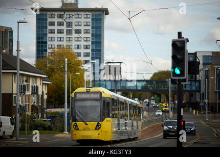 Eine gelbe Manchester Metrolink tram an Hollyhedge Straße, Benchill, Wythenshawe. Dorf 135 Ruhestand Gehäuse für die über 55 ist Stockfoto