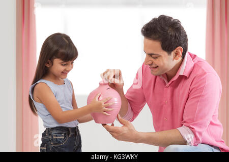 Vater und Tochter die Münze in piggy Bank Stockfoto