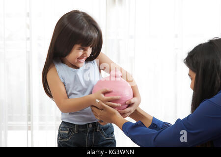 Mutter und Tochter Rucken durch Kraft Sparschwein einander Stockfoto