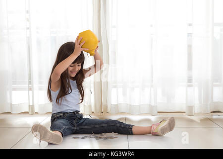 Aufgeregt Mädchen entleeren Münzen von Sparschwein Stockfoto