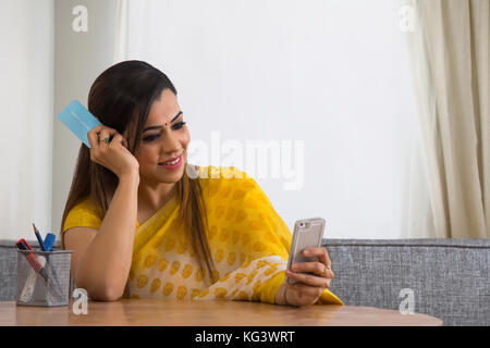 Frau mit Smartphone und Kreditkarte für die Zahlung der Rechnungen Stockfoto