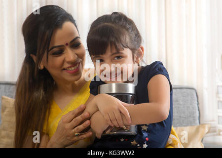 Lächelnde Mutter und Tochter Holding coin Box Stockfoto