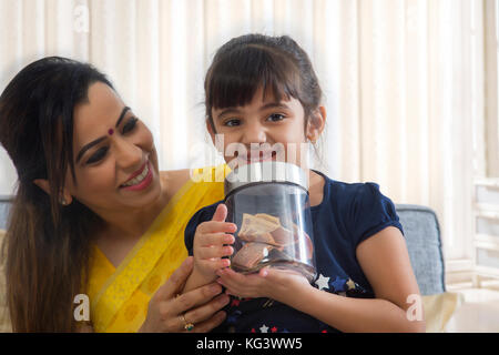 Mutter an ihre Tochter Holding coin Box Stockfoto