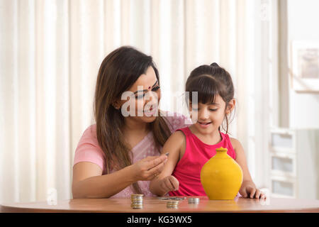 Mutter und Tochter zählen und der Hinterlegung Münzen in piggy Bank Stockfoto