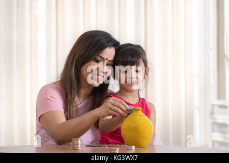 Mutter und Tochter Füllung Sparschwein Stockfoto