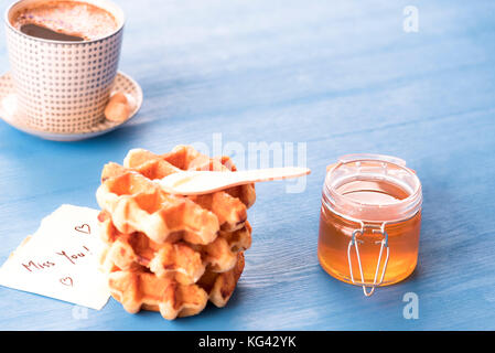 Leckeres Frühstück mit frischen Waffeln mit Honig, eine heiße Tasse Kaffee und ein nettes Papier Hinweis mit der Nachricht, die Sie fehlt, unter der es lichter Morgen wird, auf einer b Stockfoto