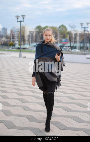 Hübsches Mädchen in warmen wolle Mantel und Schal um den Hals gewickelt zu Fuß auf der Straße. Urban Style Hüfthose. Stockfoto