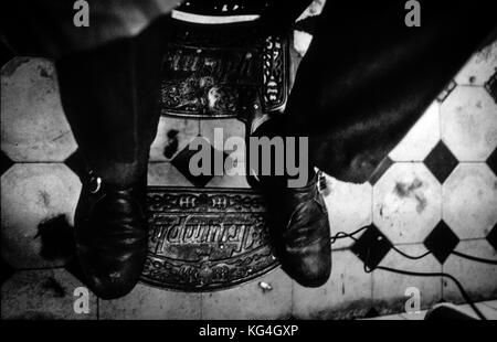 Detail eines Kunden auf einem Friseurstuhl im ausgestorbenen Peluqueria 11 Friseurladen der Tallers Street in Barcelona, Spanien. Datum: 03/2003. Foto: Xabier Mikel Laburu. Vicens Amat war das letzte Eigentum des Barbershops. Der Vater von Vicens war der erste der zweigenerationenigen Geschichte des Barbershops. Obwohl Vicens Amat nie gerne als Friseur arbeitete, kombinierte er sein Studium mit der Arbeit im Laden, hauptsächlich mit der Buchhaltung. 1982 stirbt sein Vater und er beschließt, seinen jetzigen Job als Gymnasiallehrer zu verlassen und Vollzeit im Friseurladen zu arbeiten. Der Rückgang der Kundenzahlen, die com Stockfoto