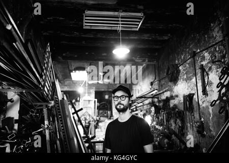 Portrait von Gustavo Bernabé, Eigentümer einer zweihundert Jahre alten Werkstatt namens Cerrajería Isabel Romero in der Abad Safont Straße in Barcelona, Spanien. Datum: 16/09/2015. Seit ca. 1815 geöffnet hat sich dieser Workshop mehrmals in die Hände gewechselt. Im Jahrzehnt der 50er Jahre begann Gustavos Vater, der aus Almeria ausgewandert war, dort zu arbeiten, und als der frühere Besitzer in den Ruhestand ging, gab er das Geschäft Gustavos Vater. Im vergangenen Jahr zog sich auch sein Vater zurück und er entschied sich, das Geschäft zu übernehmen. Da es sich um ein Immobiliengeschäft handelt, hat er keine Probleme mit der Vermietung Stockfoto