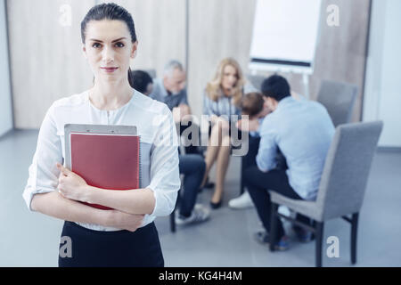 Aufmerksame Frau umarmt Ordner mit Dokumenten Stockfoto