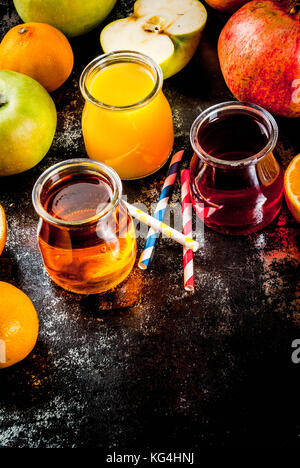 Frisches Obst und Säfte. Orangen-, Granatapfel- und Äpfel. Dunkle Rusty Hintergrund Kopie Raum Stockfoto