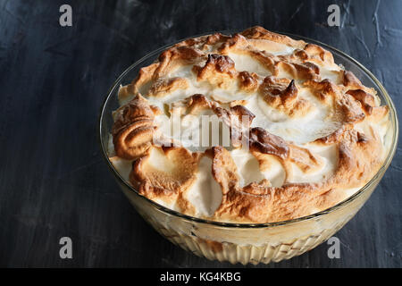 Hohe Engel Blick auf hausgemachte Banana Pudding mit Baiser von Grund auf neu über einen rustikalen dunklen Hintergrund gemacht. Stockfoto