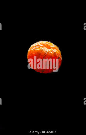 Geschälte Clementine auf schwarzen Hintergrund mit Licht durch Sie Stockfoto