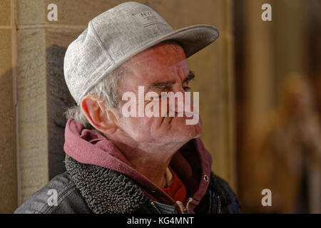 Obdachloser in Glasgow, die unterhält, Popeye Eindrücke in einem Baseball Hut gurning Stockfoto