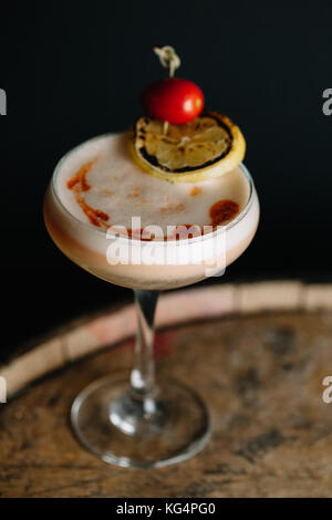 Einen alkoholfreien Cocktail mit Schaum, garniert mit Trauben Tomaten und eine Scheibe geräucherter Zitrone auf dunklem Hintergrund Stockfoto