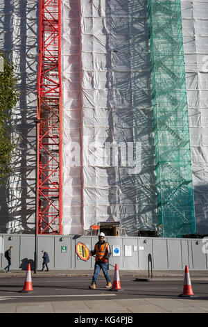 Ein Bauarbeiter klettert ein hohes gantry Turm neben einem Kran an der Seite eines Bürogebäudes gebunden (ehemals Express Zeitung) am südlichen Ende der Blackfriars Bridge renoviert wird, am 27. Oktober 2017 in London, England. Stockfoto