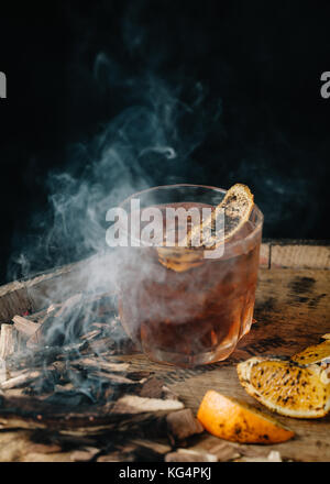 Geräucherter altmodische Cocktail garniert mit einer Orangenhaut auf dunklem Hintergrund Stockfoto