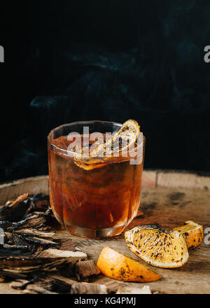 Geräucherter altmodische Cocktail garniert mit einer Orangenhaut auf dunklem Hintergrund Stockfoto