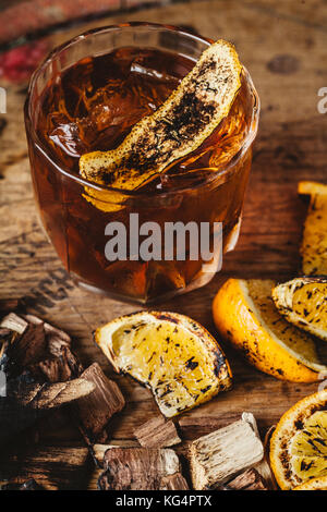 Geräucherter altmodische Cocktail garniert mit einer Orangenhaut auf dunklem Hintergrund Stockfoto