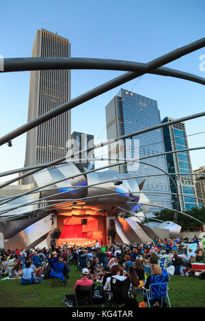 Millennium Park, Masse am Grant Park Symphony den Jay pritzker Pavilion, einer Konzertmuschel, entworfen von Frank Gehry, Hochhäuser der Innenstadt auf der Rückseite Stockfoto