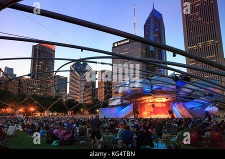 Millennium Park, Masse am Grant Park Symphony den Jay pritzker Pavilion, einer Konzertmuschel, entworfen von Frank Gehry, Hochhäuser der Innenstadt auf der Rückseite Stockfoto