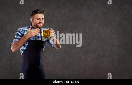 Der Brauer in seiner Schürze schnuppert den Duft von frisch gebrautes Bier. Stockfoto