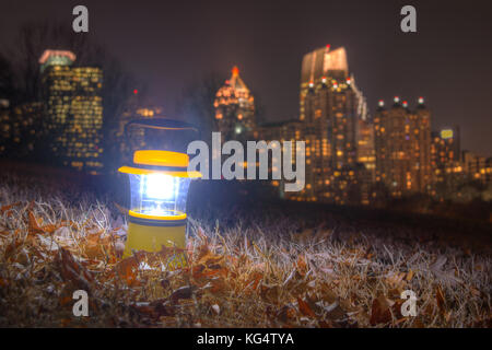 Leuchtende hand Laterne stehend auf dem Boden der Piedmont Park auf dem Hintergrund von Midtown Atlanta in der Dämmerung Stockfoto