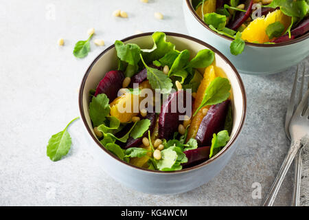 Hausgemachte Snacks auf der Küche Holztisch. Salat mit roten Rüben, Orange, Rucola und Pinienkernen. Stockfoto