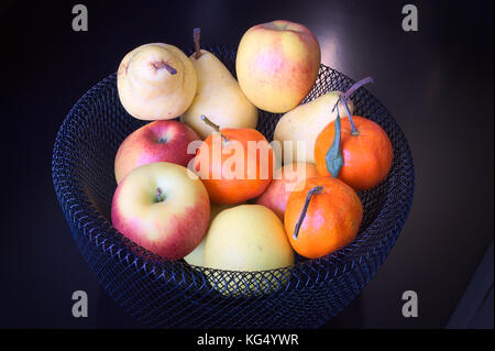 Schwarze Früchte Korb mit Äpfeln, Birnen und Mandarinen Stockfoto