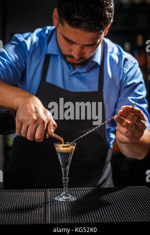 Der Barkeeper macht Gehirn Cocktail in ein Schnapsglas Stockfoto