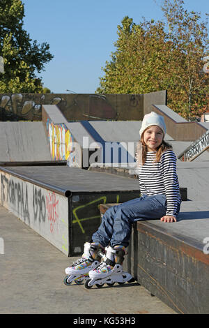 Glückliche kleine Mädchen mit rollerskates auf dem Spielplatz Stockfoto