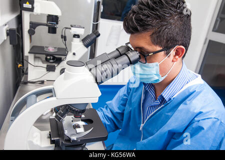 Junge männliche Wissenschaftler an Folien suchen unter dem Mikroskop Stockfoto