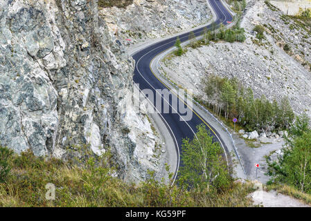 Einen malerischen Blick von oben auf eine gewundene Asphaltstraße durch einen Pass, Teil eines Berges Serpentine, Felsen und Bäume Stockfoto