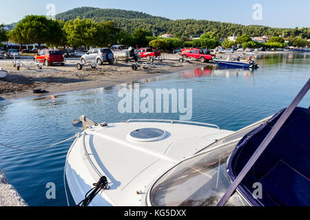 Vorderseite, Deck eines kleinen Fischerboot, schwimmend auf eine ruhige Wasseroberfläche. Im Hintergrund Leute sind entladen kleine Motorboote im Meer. Stockfoto