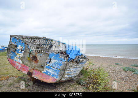 Alte blaue und rote havarierten Boot auf einem Kieselstrand in Aldeburgh, Suffolk Stockfoto