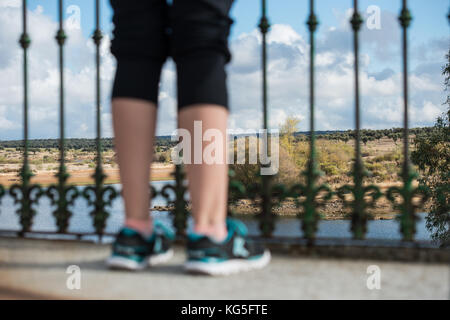 Sportliche Frau, die Beine auf einem Balkon über eine schöne Landschaft in der Extremadura, Spanien. Stockfoto