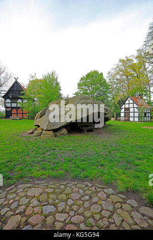 Der große erratische Block von Tonnenheide in einem Eichenwald mit Fachwerkhäusern an der Westfälischen Mühlenstraße (Route), Deutschland, Landkreis Minden-Lübbecke Stockfoto