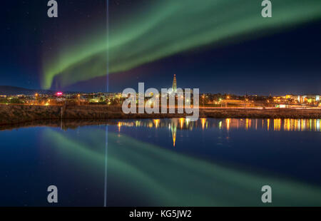 Aurora borealis und der Lichtstrahl aus der Imagine Peace Tower, Reykjavik, Island Stockfoto