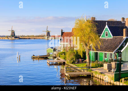 Holzhäuser und Mühle sind im blauen Wasser des Flusses Zaan zaanse schans North Holland Niederlande Europa Stockfoto