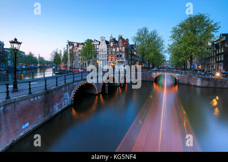 Dämmerung leuchtet auf die typischen Gebäude und Brücken spiegeln sich in einer typischen Kanal Amsterdam Holland die Niederlande Europa Stockfoto