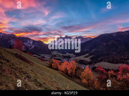 Bunte Herbstbäume umrahmen die Geislergruppe und das Dorf St. Magdalena bei Sonnenaufgang im Funes Tal Südtirol Dolomiten Italien Europa Stockfoto