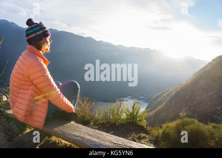 Junge Frau sitzt auf dem Zweig auf dem Aussichtspunkt, Entspannung nach Wandern und Beobachten die Bohinj See, Slowenien Stockfoto
