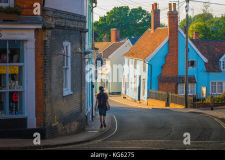 Framlingham Suffolk UK, an einem Sommerabend ein Jugendlicher mit einem Skateboard Spaziergänge entlang der Bridge Street in Suffolk Stadt Framlingham, England, Großbritannien Stockfoto