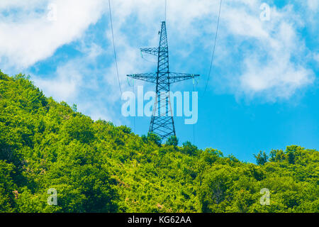 Ein Sendemast steht in der Mitte des Waldes auf der Spitze eines Berges im sonnigen Sommertag Stockfoto