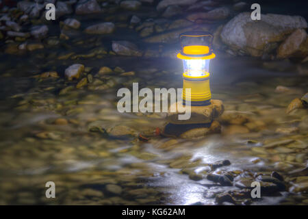 Leuchtende hand Laterne stehend auf dem Stein, im fließenden Wasser des Flusses liegend Stockfoto