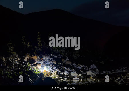 Leuchtende hand Laterne stehend auf Felsen der Schlucht auf dem Hintergrund der Silhouette von tamyurdepe Berg bei Dämmerung, Sochi, Russland Stockfoto