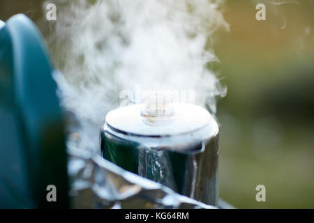 Dampf wogenden aus einem kochenden Topf der Flüssigkeit in einem Behälter aus Edelstahl Gasbrenner auf einem Campingplatz in der Nähe zu sehen. Stockfoto